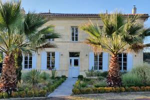 a house with palm trees in front of it at Villa l'Estuaire Chambres d'Hôtes in Braud-et-Saint-Louis