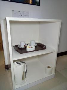 a white shelf with cups and dishes on it at Motel Fyna in Kangar