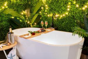 eine Badewanne mit Weingläsern und eine grüne Wand in der Unterkunft Bella Paradiso in Airlie Beach