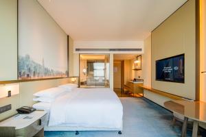 ein Hotelzimmer mit einem großen Bett und einem Flachbild-TV in der Unterkunft Four Points by Sheraton Wuhan, Jiangxia in Wuhan