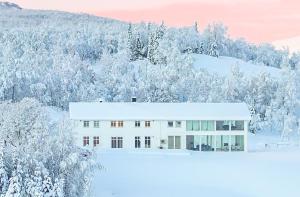 a white house in the snow with trees at Aurora Borealis Observatory in Silsand