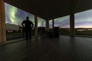 a man standing in front of a window looking at the sky at Aurora Borealis Observatory in Silsand