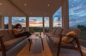a woman sitting on a couch in a room with windows at Aurora Borealis Observatory in Silsand