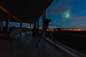 a person sitting on a balcony with a camera on a tripod at Aurora Borealis Observatory in Silsand