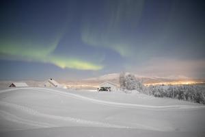 a snow covered field with houses in the distance at Aurora Borealis Observatory in Silsand