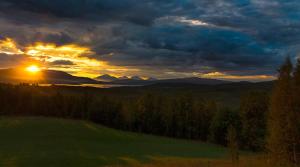 a sunset over a field with mountains in the background at Aurora Borealis Observatory in Silsand