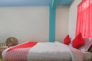 a bedroom with a bed with red and white pillows at OYO Bell's Bigxa Homestay in Cherrapunji