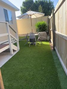 a backyard with an umbrella and chairs and a lawn at LOVELY PET FRIENDLY SELF CONTAINED HOLIDAY VILLA in Bongaree