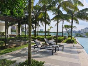 a patio with two chairs and palm trees next to the water at Sandy Suite by SM Hub in Cyberjaya
