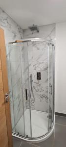 Una ducha en una habitación con paredes de mármol. en Town Centre Apartment, en Leek