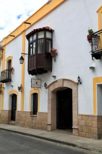 a white building with a balcony and a door at El Hotel de Su Merced in Sucre