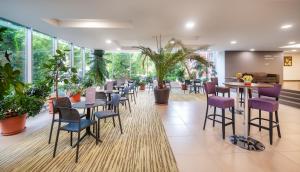 un restaurante con mesas, sillas y plantas en Hunguest Hotel Gyula, en Gyula