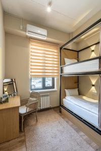 Bodo Hostel في بيشكيك: غرفة نوم مع سرير بطابقين ومكتب وكرسي