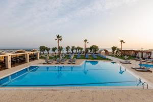 een groot zwembad met stoelen en palmbomen bij Malia Bay Beach Hotel & Bungalows in Malia