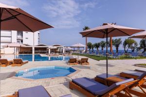 uma piscina com cadeiras e guarda-sóis em Malia Bay Beach Hotel & Bungalows em Malia