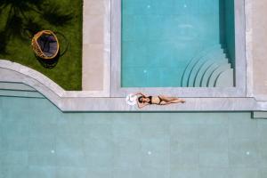 une femme se posant sur le côté d'une piscine dans l'établissement Malia Bay Beach Hotel & Bungalows, à Mália