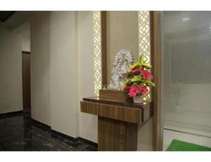 a room with a console with flowers on it at Hotel Leisure, Ahmedabad in Ahmedabad