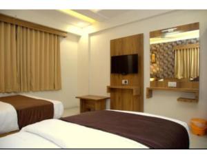 a hotel room with two beds and a flat screen tv at Hotel Leisure, Ahmedabad in Ahmedabad