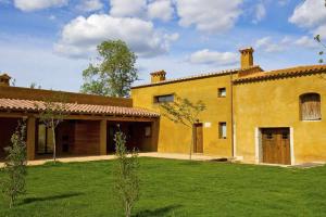 uma grande casa amarela com um jardim verde em Mas Garriga Turisme Rural em Girona