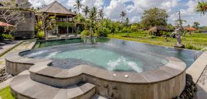 a swimming pool in a yard with a house at Anumana Village Ubud in Ubud