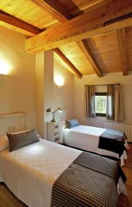2 bedden in een slaapkamer met houten plafonds bij Mas Garriga Turisme Rural in Girona