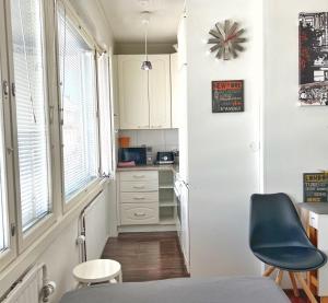 a small kitchen with white cabinets and a blue chair at Sweethome Studio 48 City Center Аlbertinkatu in Helsinki