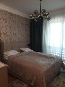 - une chambre avec un grand lit et un lustre dans l'établissement Guest House Vila Lujza, à Palić