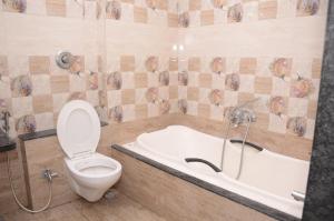 a bathroom with a toilet and a bath tub at Hotel Mangalam in Kurandvād +31 photos