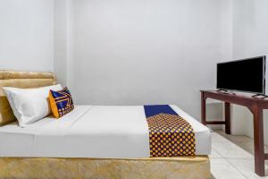 een slaapkamer met een bed, een bureau en een televisie bij Super OYO 91366 The Chatter Place in Bandung