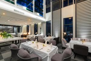 un restaurant avec des tables blanches, des chaises et des fenêtres dans l'établissement Kantary Hotel Korat, à Nakhon Ratchasima