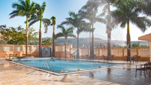 a swimming pool with palm trees and a slide at 7 Apple Resort Lonavala in Lonavala