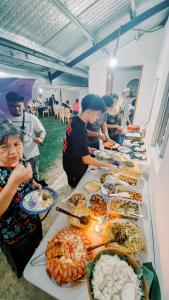 un grupo de personas de pie alrededor de una larga mesa de comida en Beach House, San Juan, La Union en San Juan