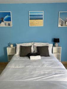 Una gran cama blanca en una habitación con una pared azul. en Summer guest house with hottub and BBQ area, en Winchmore Hill