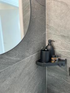 uma casa de banho com um espelho e um dispensador de sabão numa prateleira em Sea La Vie #2 - Luxury Seaview apartment em Pafos