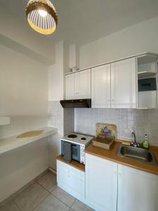 a kitchen with white cabinets and a sink and a microwave at Karaoulanis Beach in Agios Ioannis Pelio