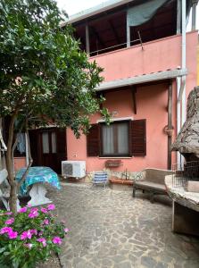 a pink house with a patio and a tree at Casa Serbariu, Sud Sardegna - Carbonia in Carbonia