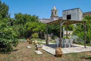 a table and chairs under a gazebo in a garden at La dimora Elia' in Muro Leccese