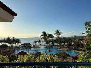a view of a resort pool with palm trees and the ocean at Canyon Cove by Lawton in Nasugbu