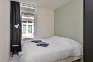 a bedroom with a white bed and a window at Hertog 1 Modern and perfectly located apartment in Eindhoven