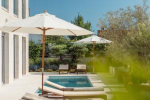 a swimming pool with two umbrellas and lounge chairs and a swimming pool at Villa Roc Blanc in Tivat