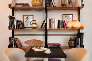 a table and two chairs in front of a book shelf at Hotel Pulitzer Paris in Paris