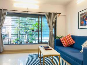 a living room with a blue couch and a window at Matruchaya, off Carter Road by Connekt Homes in Mumbai