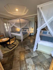 a bedroom with two beds and a table and a bedvisor at Heart and Soul Lodge in Karatu
