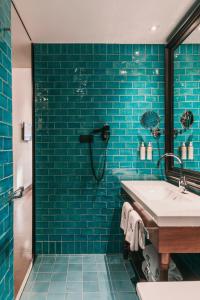 a blue tiled bathroom with a sink and a shower at Hotel Pulitzer Barcelona in Barcelona