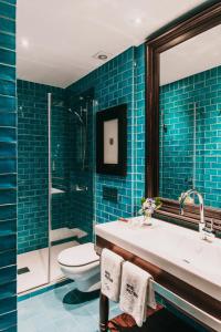 a bathroom with a sink and a toilet and blue tiles at Hotel Pulitzer Barcelona in Barcelona