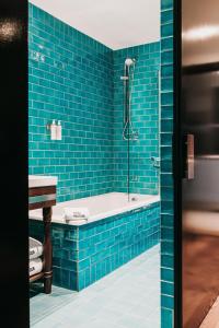 a blue tiled bathroom with a tub and a sink at Hotel Pulitzer Barcelona in Barcelona