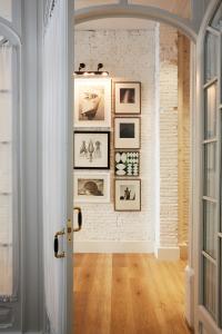 a hallway with pictures on a white brick wall at Hotel Pulitzer Barcelona in Barcelona