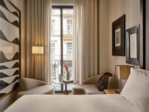 a hotel room with a bed and chairs and a window at Hotel Pulitzer Barcelona in Barcelona