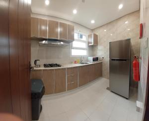 a kitchen with wooden cabinets and a stainless steel refrigerator at Al Sabeel Building in Salalah