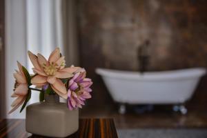 a vase with flowers on a table in a bathroom at Hotel Monarch in Batumi